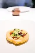 One onion ring served with capers on top.