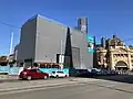 Acoustic box over the Federation Square entrance to Town Hall station, with Flinders Street station in the background, August 2022