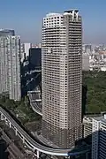 Aerial view of a brown and beige, rectangular, window-dotted high-rise