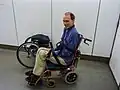 An aisle chair being used to transport a man into an aircraft at Brisbane Airport