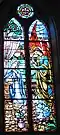 The Annunciation – The angel of God announces to the Virgin Mary that she is to be the mother of Jesus, the Messiah. The symbols in the window relate to Mary. The circle at the top is the "fleur-de-lis," symbol of the Virgin Mary.