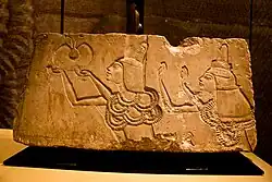 Stone relief of a man and woman with raised arms