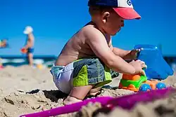 Image 7A young boy playing with a toy dump truck at the beach. (from Boys' toys and games)