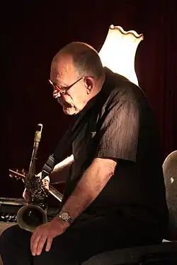 A man holding a saxophone looking at some music