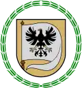 A coat of arms depicting a white flag with a black bird on it with a yellow beak and yellow claws all on a yellow background