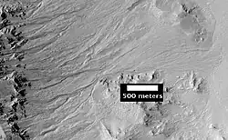 Gullies. Notice how channels curve around obstacles, as seen by HiRISE.