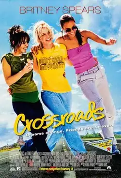 Three young women walking along a highway against a blue sky