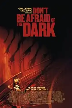 In a red lit room, shadows of a group of clawed creatures' arms reach towards a little girl.