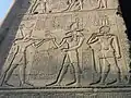 a relief from the temple of Esna. Heka, the rightmost god is wearing a hemhem