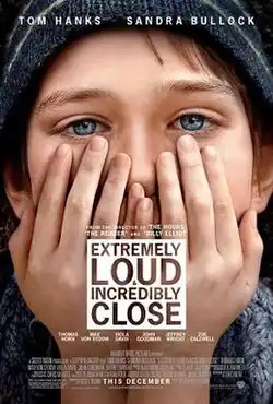 A blue eyed boy, with his hands covering his mouth.