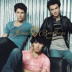 The band members siting on a couch, in a triangular position, looking forward