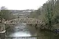 Most of the development on one side of the valley – footbridge over the River Derwent