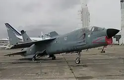 Left three-quarter view of an F-8P Crusader. This aircraft is in the livery applied in the 1990s of dark grey-blue with the number 10 on its side. The aircraft's wings are folded