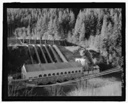 B&W image of powerhouse in the foreground with the back sided of the dam in the foreground.