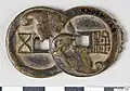 A gourd charm which looks like two Wu Zhu coins with bat figures obscuring the character at their intersection