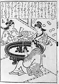 Two women and a man warming themselves by a hibachi