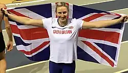 Holly Bradshaw in a Great Britain t-shirt draped in a British flag.