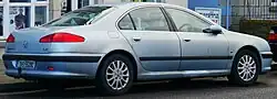Rear-three-quarter view of a four-door car with a three-box body style whose rear luggage compartment is separate from the passenger cockpit