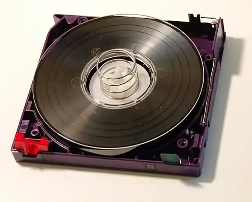 LTO-2 cartridge with the top shell removed, showing the internal components. Top right corner: tape access gate. Bottom left corner: write-protect-tab. Bottom right corner: cartridge memory chip