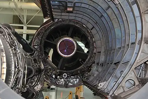 A rear view of the inlet where air enters the engine. Two features were added after flight testing highlighted the need: 1) "mice," visible as streamlined shapes, added to reduce the diffusion rate after pilots noted rumbling; and 2) rear bypass doors added to prevent unstarting the inlet during descents with low engine flow.[77] The ring of doors is at the extreme rear of the inlet as shown by their accompanying rear-turning scoop, extending from 7 o'clock to 5 o'clock, which directs the air through the nacelle to the ejector nozzle.[78] The door actuator[79]