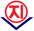 A blue circle with red lettering inside it; underneath the circle is a red V