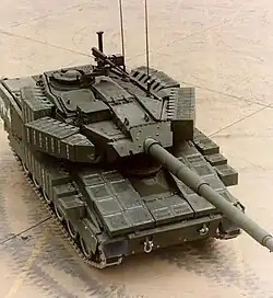An AGS as seen from a high angle. Thick boxes cover the sides of the turret, track skirts and glacis plate. The commander's station is armed with an M2 Browning .50 caliber machine gun.