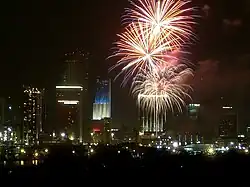 Tower lit as American flag on 4th of July, showing fireworks in foreground