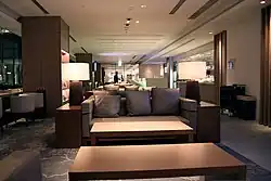 A three-seater couch with two coffee tables in the front and two side tables on both side, all in neutral brown color