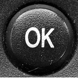 "A round push button with the letters O and K as labels.