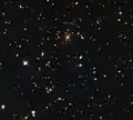 Jellyfish galaxy in SDSS J1110+6459, visible next to the cluster and apparently dripping bright blue material.[6]