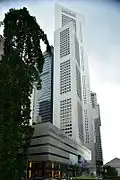 Ground-level view of 60-storey building whose cross section is a square with a diagonal projection from one corner. In the top 10 storeys part of the square is missing and only a diagonal remains.