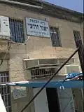 Exterior sign stating that the synagogue was supported by philanthropist Yamin Ben Harroch, and founded in the year 1927.