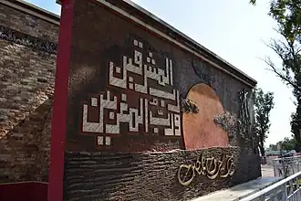 Monument on the mosque's west side featuring Quranic verse 55:17