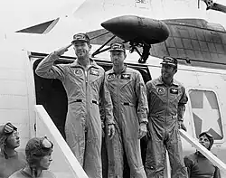 Three men in flight suits disembark a helicopter