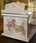View of one side of the sarcophagus with paintings and the gabled roof.