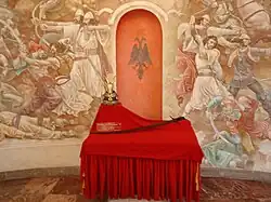 Mural commemorating a battle of Skanderbeg. The Arms of Skanderbeg visible in the forefront are copies of the originals held at the Imperial Armoury of Vienna.