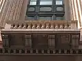 A close-up of the building's distinctive terracotta and pink granite façade.