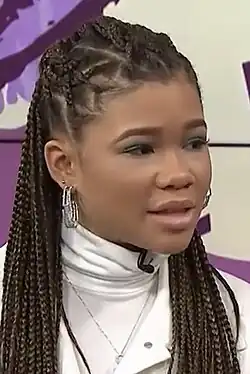 16 year-old girl with long, braided hair talking to something to the right.