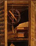 An armillary sphere, books, and a quadrant depicted through the use of intarsia