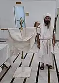 Tarmida Sahi Bashikh standing next to a drabsha, at Yahya Yuhana Mandi during Parwanaya 2025