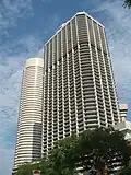 Ground-level view of 50-storey box-like building with dark, receded windows and cut-off, diagonal corners