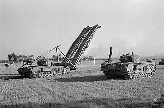 A tank with a section of bridge held out at 45 degrees in front of it, with another tank to its side