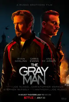 Two men standing back to back are lit in red-orange lighting in contrast to the navy blue sky city background.