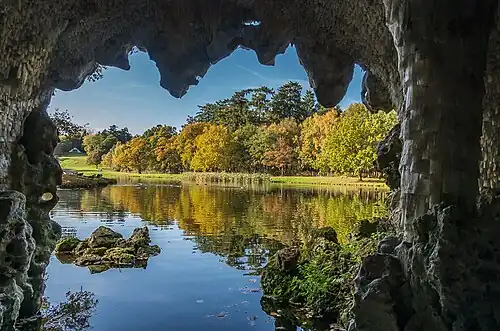 A roughly square opening in a side of a cavern through which a lake can be seen