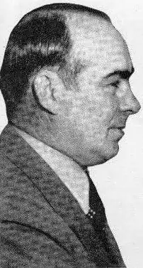 Black and White picture. Profile of a man facing right. He has tidy hairs and wears a suit with a cravat. We can only see the bust.
