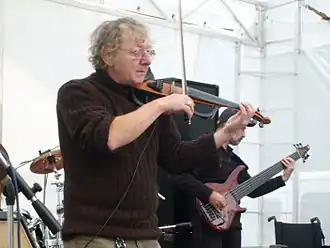 Jan Hrubý standing onstage with another musician, playing a violin