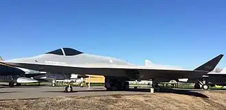 The YF-23 painted light gray, the "Spider", can be seen at the center with its labels. An unmarked fighter jet is at its left, and a Navy aircraft is to the right, marked VF-2, probably the squadron it belonged to.
